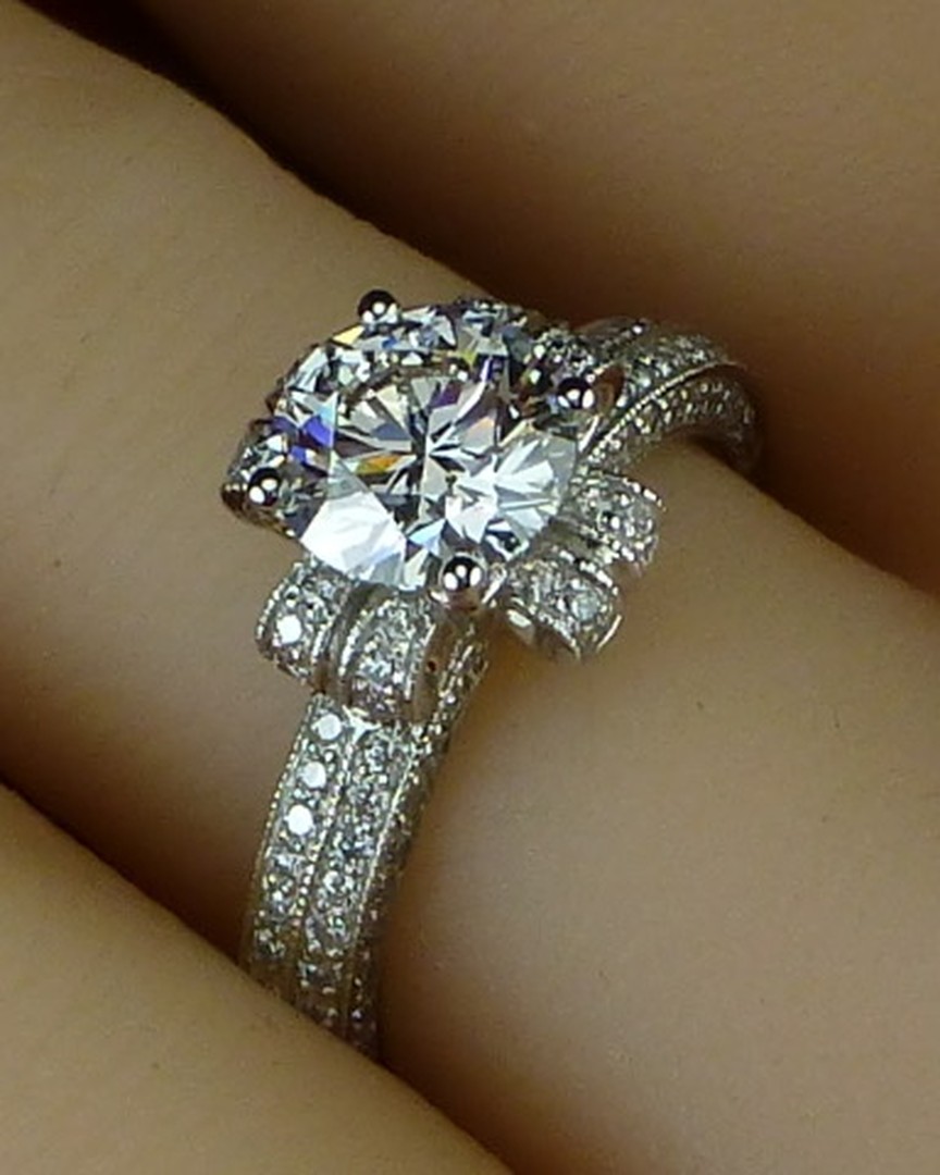 A round diamond ring with bow-shaped pavé shoulders, worn on a finger