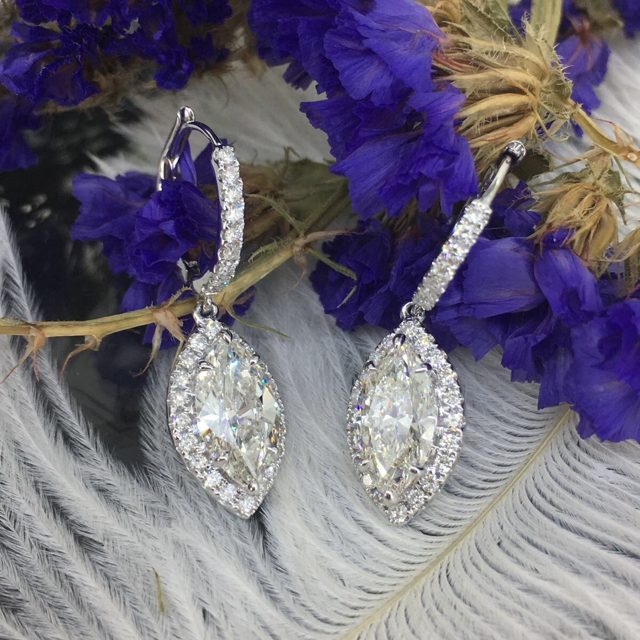 Marquise diamond halo drop earrings among purple flowers