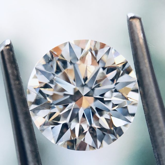 Round brilliant loose diamond held in tweezers