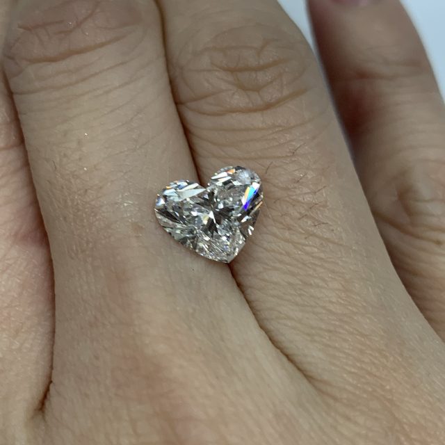 Heart-shaped loose diamond resting on a finger
