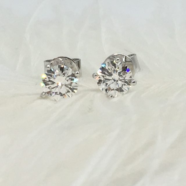 Round diamond stud earrings on white feathers