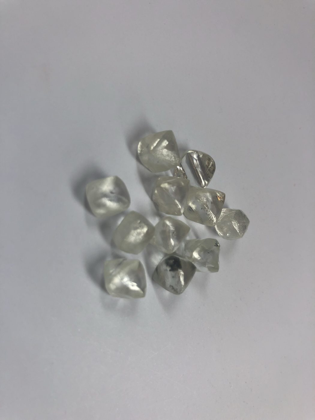 Close-up of a handful of octahedral rough diamonds, some with dark inclusions