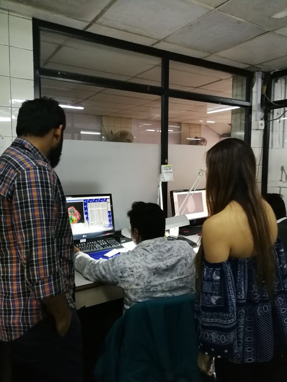 Standing behind a technician reviewing a rough diamond's 3D model on screen