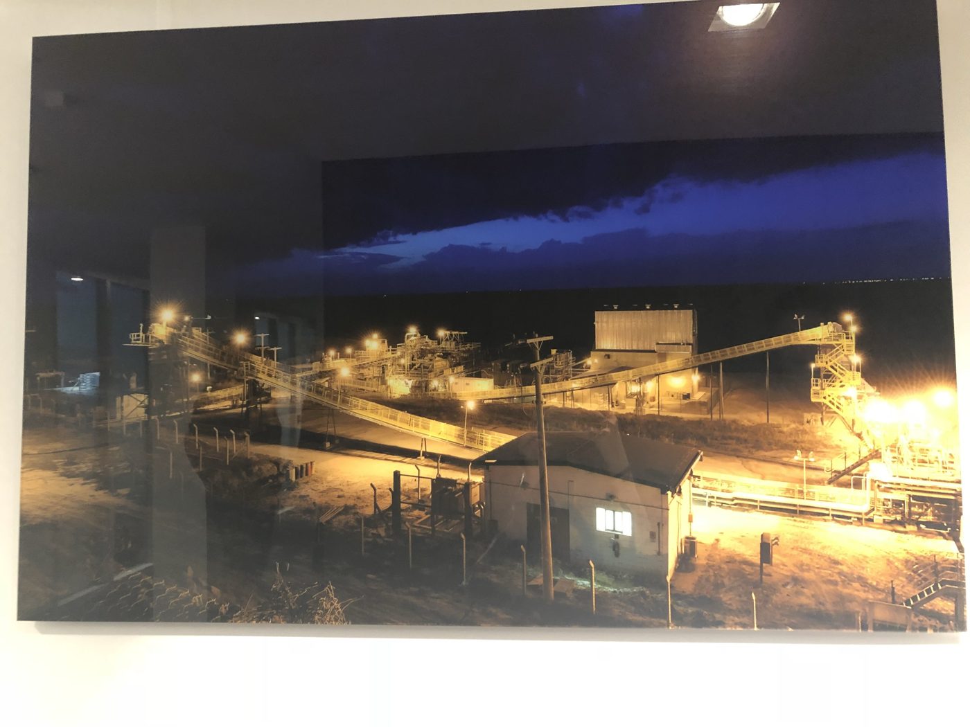 A framed night photograph of a diamond mine's processing plant with lit conveyor belts